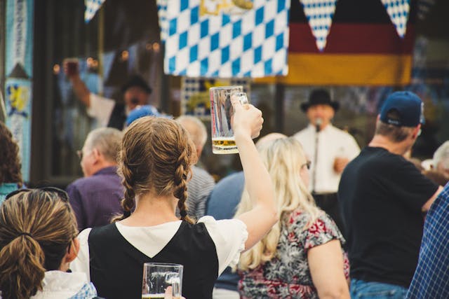 Woman raising a beer glass at a lively outdoor festival.